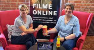 Büchereileiterin Gaby Maidorn (links) und Helga Wiedermann (rechts) machen schon einmal den Streaming-Test, natürlich mit Popcorn. Foto: Gemeinde Seevetal