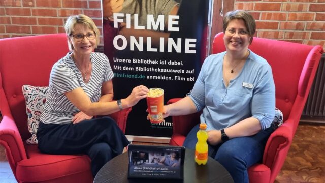 Büchereileiterin Gaby Maidorn (links) und Helga Wiedermann (rechts) machen schon einmal den Streaming-Test, natürlich mit Popcorn. Foto: Gemeinde Seevetal