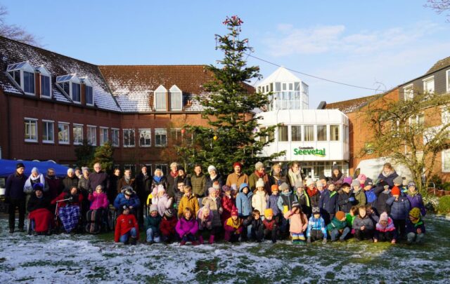 Bewohnerinnen und Bewohner des Hauses Huckfeld sowie die Kinder von drei ersten Klassen der Grundschule Hittfeld vor dem geschmückten Baum. Foto: Gemeinde Seevetal