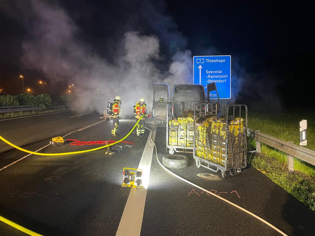 Mehrere mit Postkisten beladene Rollwagen zogen die Einsatzkräfte aus dem brennenden Transporter. Foto: Feuerwehrleute löschen den Fahrzeugbrand auf der A7 in Fahrtrichtung Thieshope. Foto: Thomas Müller