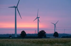 Drei Windkräfträder auf einem Feld bei Sonnenuntergang