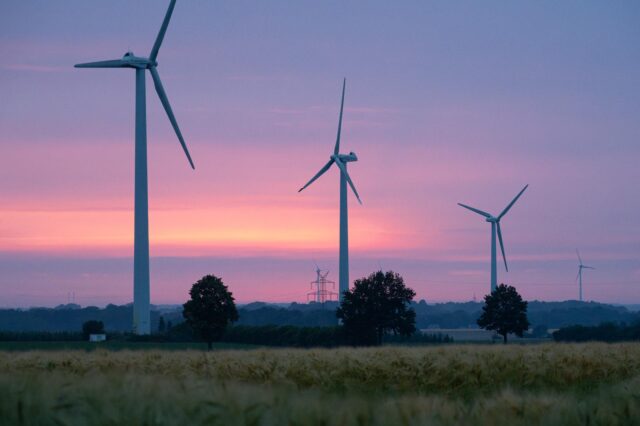 Drei Windkräfträder auf einem Feld bei Sonnenuntergang