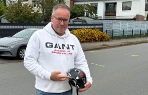 Vater Marco Walczak steht am Unglücksort in der Bürgermeister-Heitmann Straße in Meckelfeld und zeigt auf den Fahrradhelm seines Sohnes. Dieser rettete am Montagnachmittag ein Kinderleben. Foto: Hamann